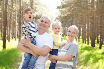 Fototapeta premium Happy grandparents with little children in forest on sunny day