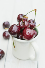 Mug filled with cherries on a wooden table