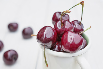 Mug filled with cherries on a wooden table