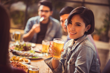 Women are drinking beer and the clink glasses in a restaurant.