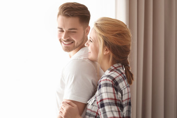 Happy young couple near window at home