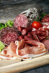 Food tray with delicious salami, pieces of sliced ham, sausage,