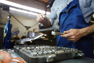 Repairman with tool doing his work in garage