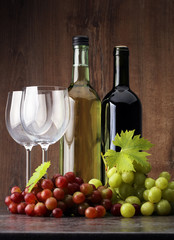 Bottle of white wine, red wine and grape on wooden table