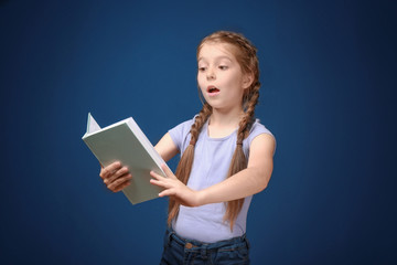 Obraz premium Cute funny girl with book on color background