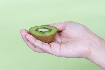 Holding kiwi fruit on green background