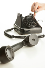 Woman's fingers dialing a vintage rotary dial telephone