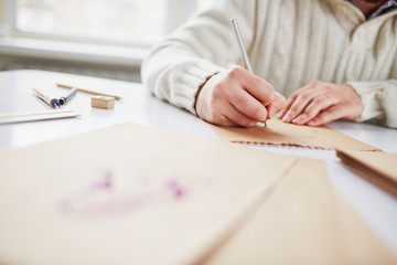 Young artist or designer with pen drawing picture on paper