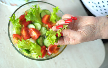 Female hands are cooking vegetable salad at the kitchen