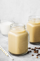 Ice coffee with milk in a tall glass on a gray background