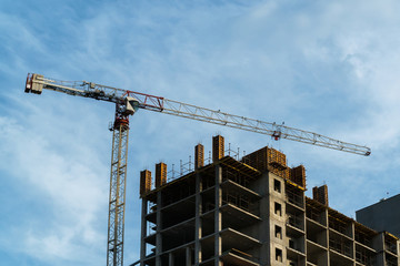 Crane lifting concrete mixer container against blue sky