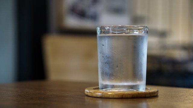 Glass of cold mineral water on the wood table of the cafe background