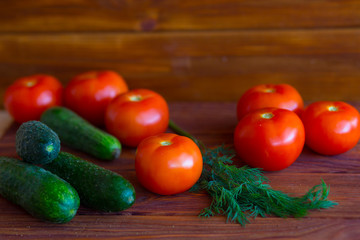 Summer vegetables on a wooden background. Cucumbers, tomatoes on the table