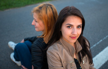 Two girls sitting back to back