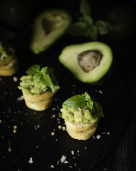 Toasts with pasta from avakado or guacamole and spices on wooden table with fruits, selective focus, concept