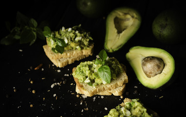 Toasts with pasta from avakado or guacamole and spices on wooden table with fruits, selective focus, concept