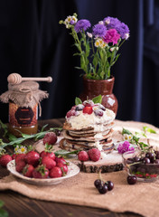 Delicious pancakes with berries and cream on the authentic wooden stand. Summer food still life concept.