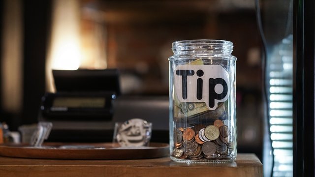 glass jar with thai baht coin on the cashier counter.
