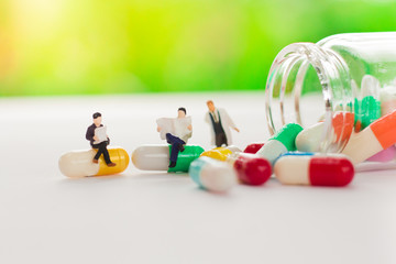 Miniature people : doctor with drug, read the medical treatments ,using as background medical concept
