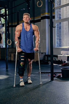 Bodybuilder on crutches in a gym club.