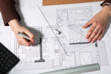 Top view of architect working at her desk with blueprints in front of her. Working on new projects. Architecture and design