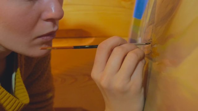 female artist painting a landscape picture on a reclaimed wooden board