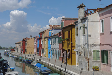 Fototapeta na wymiar BURANO - ITALY, APRIL 18, 2009: Panoramic view of colorful buildings and boats in front of a canal at Burano, a gracious little town full of canals, near Venice.