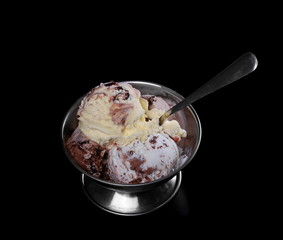 Fruit and chocolate ice cream in metal bowl isolated on black background
