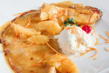 Sweet crepe with ice cream closeup. Restaurant serving of healthy morning breakfast. Homemade dessert with orange sauce on white plate.