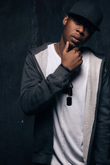 Pensive unhappy black man stay on dark background. American gangster, dangerous people, urban style...