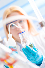 Female laboratory assistant with chemical experiment in scientific laboratory