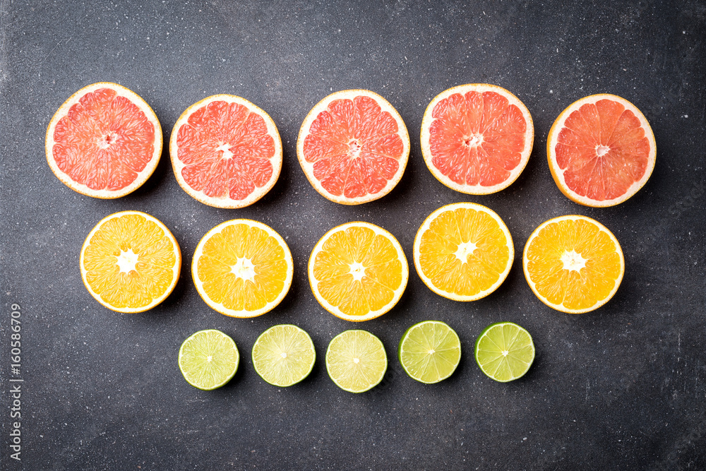 Wall mural Half of citrus fruits on dark stone background 