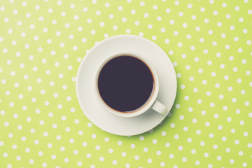 Overhead shot of of coffee cup on green dotted background
