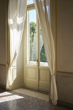 Finestre e tendaggi interni di una villa del 19 secolo con luce del sole diretta e vista sul parco 