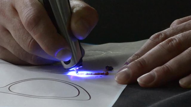 Drawing 3d pen draws with hardening photopolymer close-up. Person drawing with 3D pen that draws a liquid photopolymer that hardens under the action of the ultraphylet