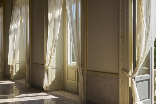 Finestre e tendaggi interni di una villa del 19 secolo con luce del sole diretta e vista sul parco 