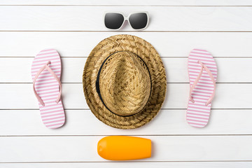 Summer background with straw hat, sunglasses, sunscreen bottle and pink flip flops