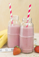 Milkshake in a glass bottle. Useful smoothies with banana, strawberries and oat, healthy breakfast.