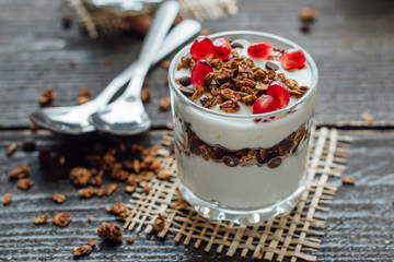 Yogurt with granola in a glass on a wooden board 