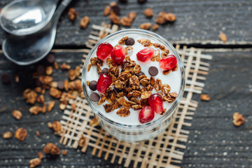 Yogurt with granola in a glass on a wooden board 