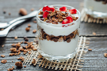 Yogurt with granola in a glass on a wooden board