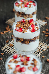 Yogurt with granola in a glass on a wooden board 