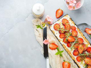 Home made strawberry not baked cheese cake in oven tin on gray background with flowers