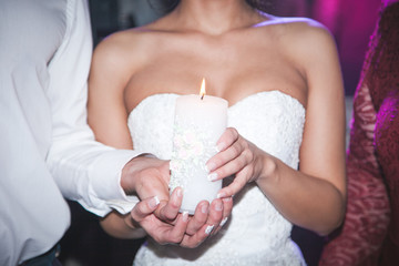Obraz na płótnie Canvas Spiritual couple, bride and groom holding candles during wedding ceremony in christian church, emotional moment during ceremony, woman's hand closeup