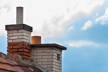 Old brick chimney on the roof. Air pollution.