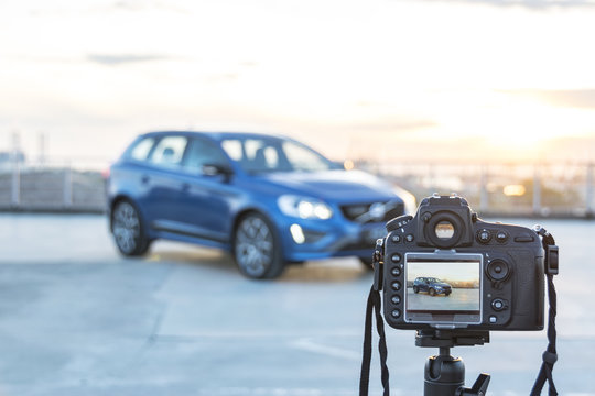 A Photo camera taking pictures of modern car on the roof of building at the sunset