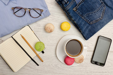 Planning a trip. Blue shirt, coffee mug, notebook and phone. Fashionable concept. Top view