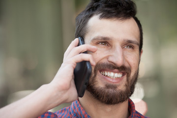 Smiling bearded man doing a phone call. Happy man in modern shirt.