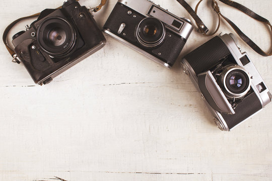 Three old retro cameras on wooden background