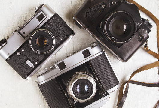 Three vintage cameras on wooden background